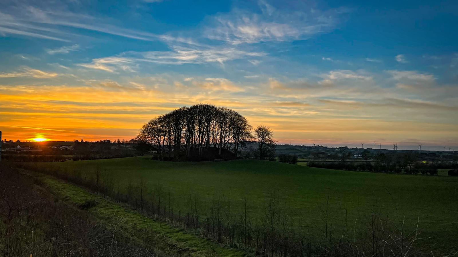 Dundermot Mound with a clear blue sky and green fields surrounding